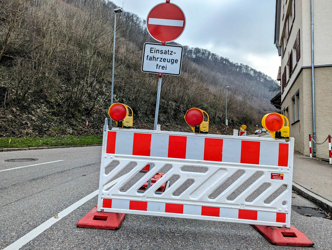 Ein weiß-roter Absperrzaun steht auf einer Straße.